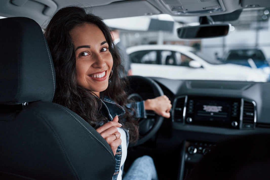Conductora capacitada del Juby Care Team en El Salvador brindando el servicio de movilidad segura: una joven profesional al volante que garantiza traslados seguros y acompañamiento integral para adultos mayores con trato humano y puntualidad.