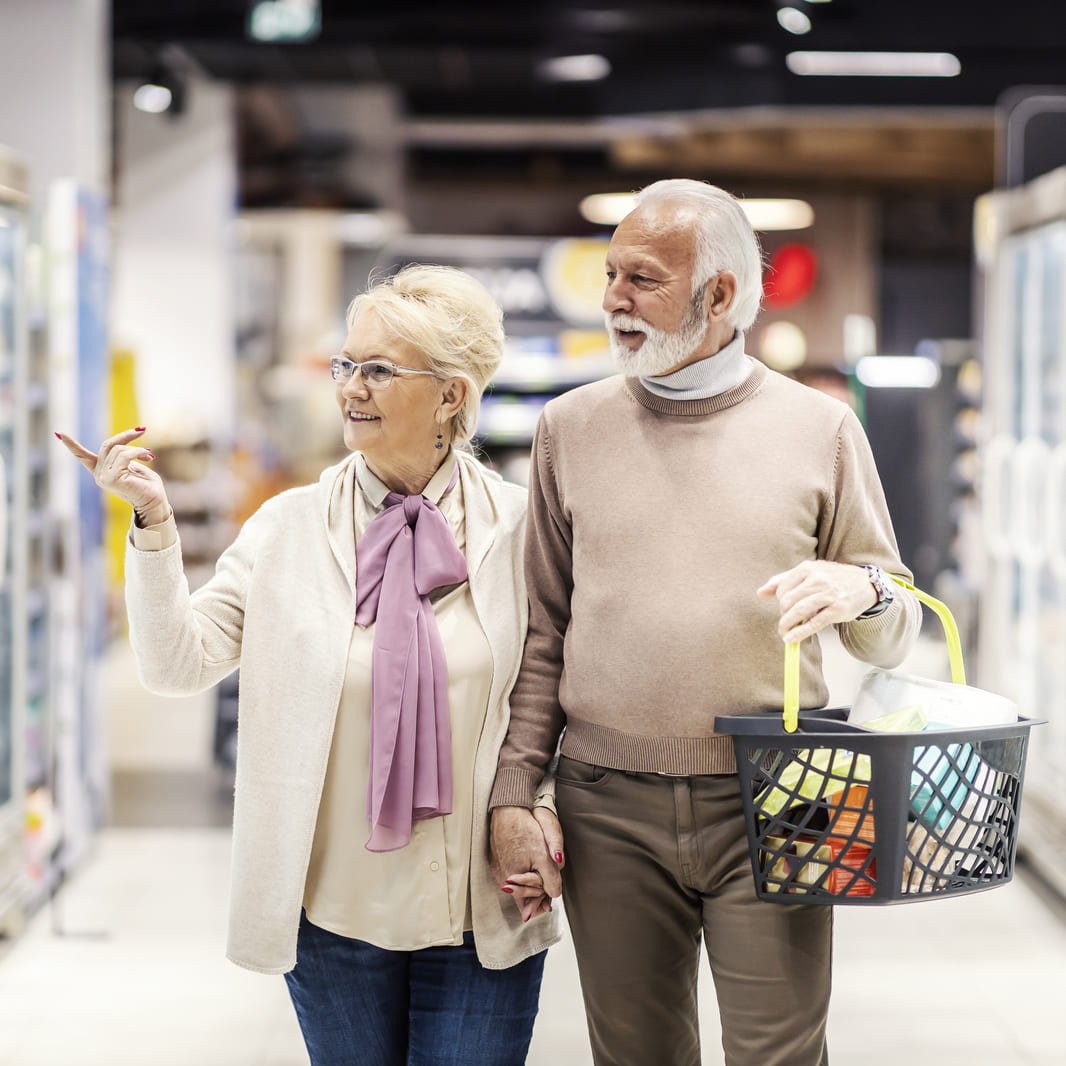 Servicio de acompañamiento para adultos mayores en supermercados: Pareja de la tercera edad realizando compras de forma segura con el apoyo de Juby Care en El Salvador.
